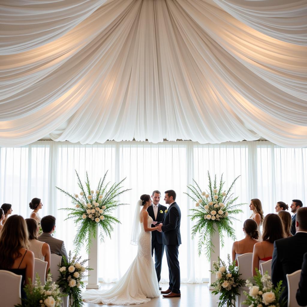  Breathtaking wedding ceremony setting featuring ceiling drapes and cascading floral arrangements.